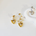 Gold heart-shaped earrings with pearls on a white background
