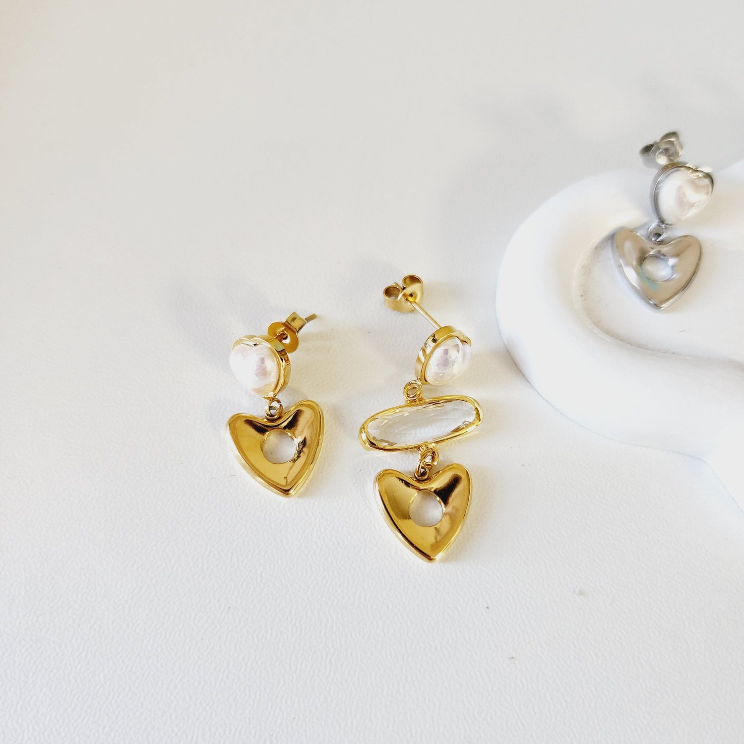 Gold heart-shaped earrings with pearls on a white background