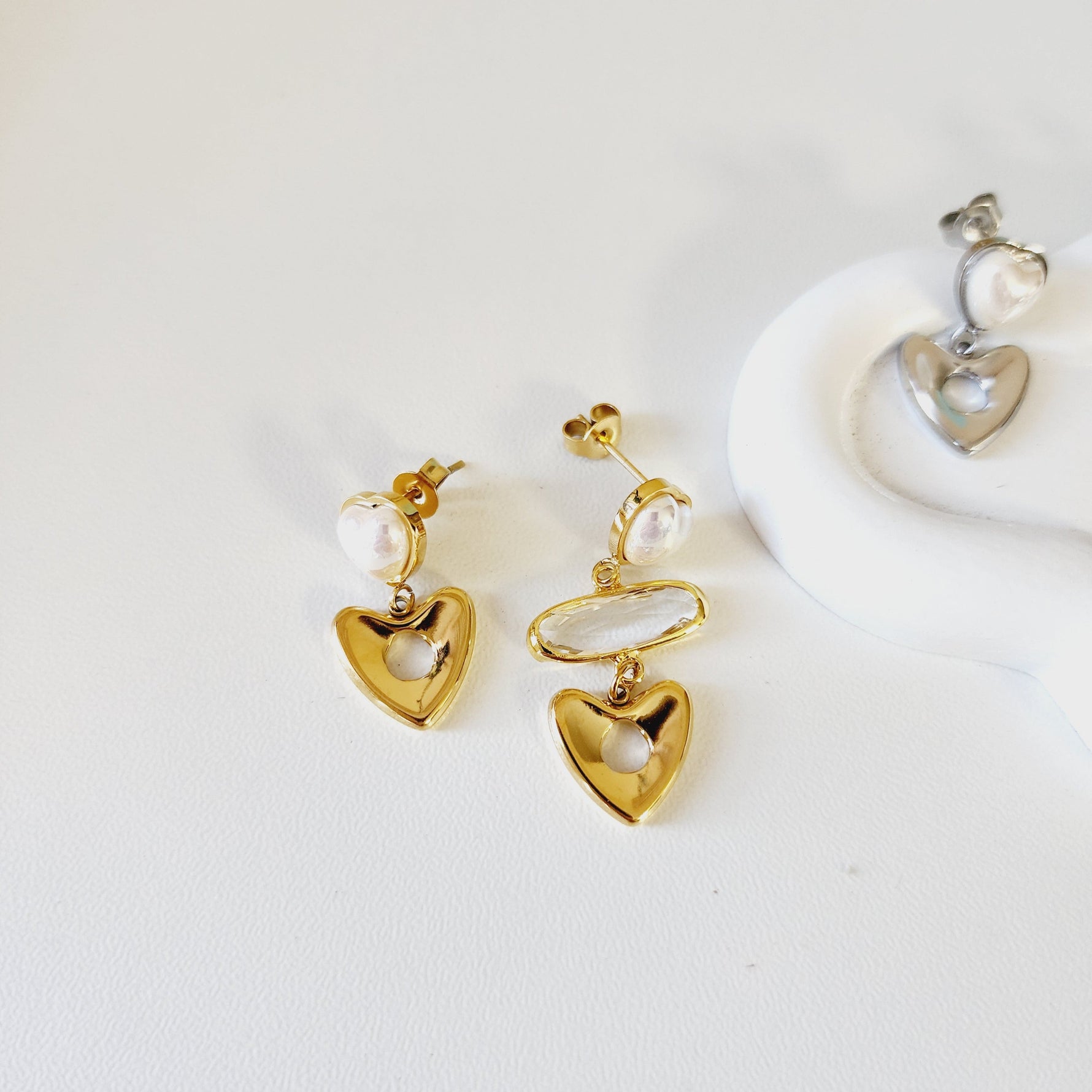 Gold heart-shaped earrings with pearls on a white background