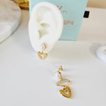Gold earrings on a white surface with a blue box in the background